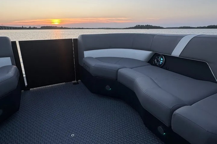 Boat interior with gray seats at sunset over a calm lake.
