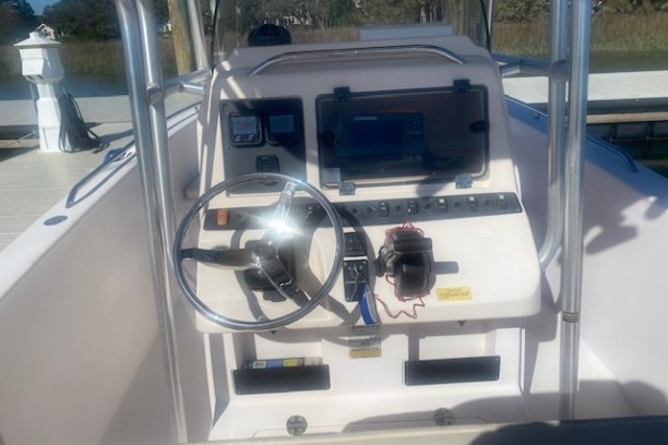 Boat helm with steering wheel, dashboard, and electronic display.
