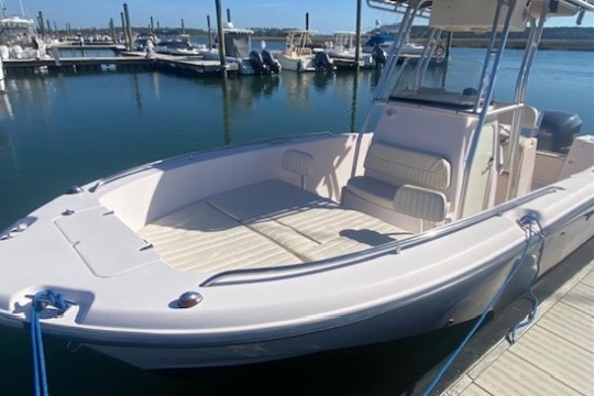 A small white motorboat docked at a marina on a sunny day.