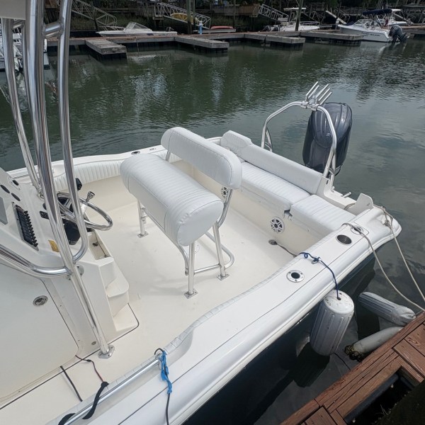 White boat docked at a marina with seating and engine visible.