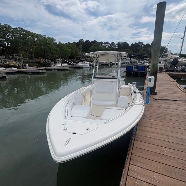 White boat docked beside a wooden pier under a cloudy sky.